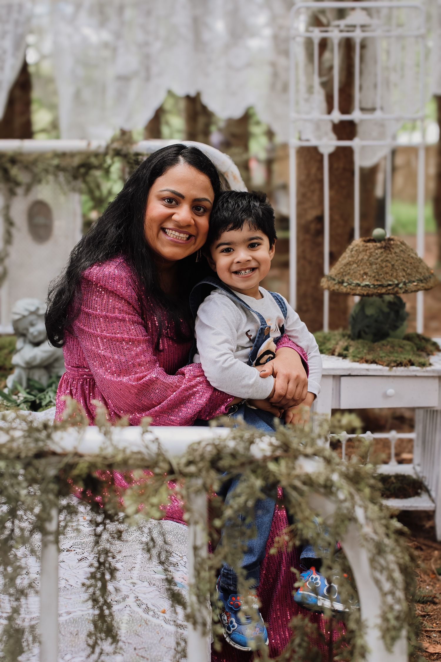 A joyful parent and child share loving moments together in an outdoor setting with natural foliage and white railings.