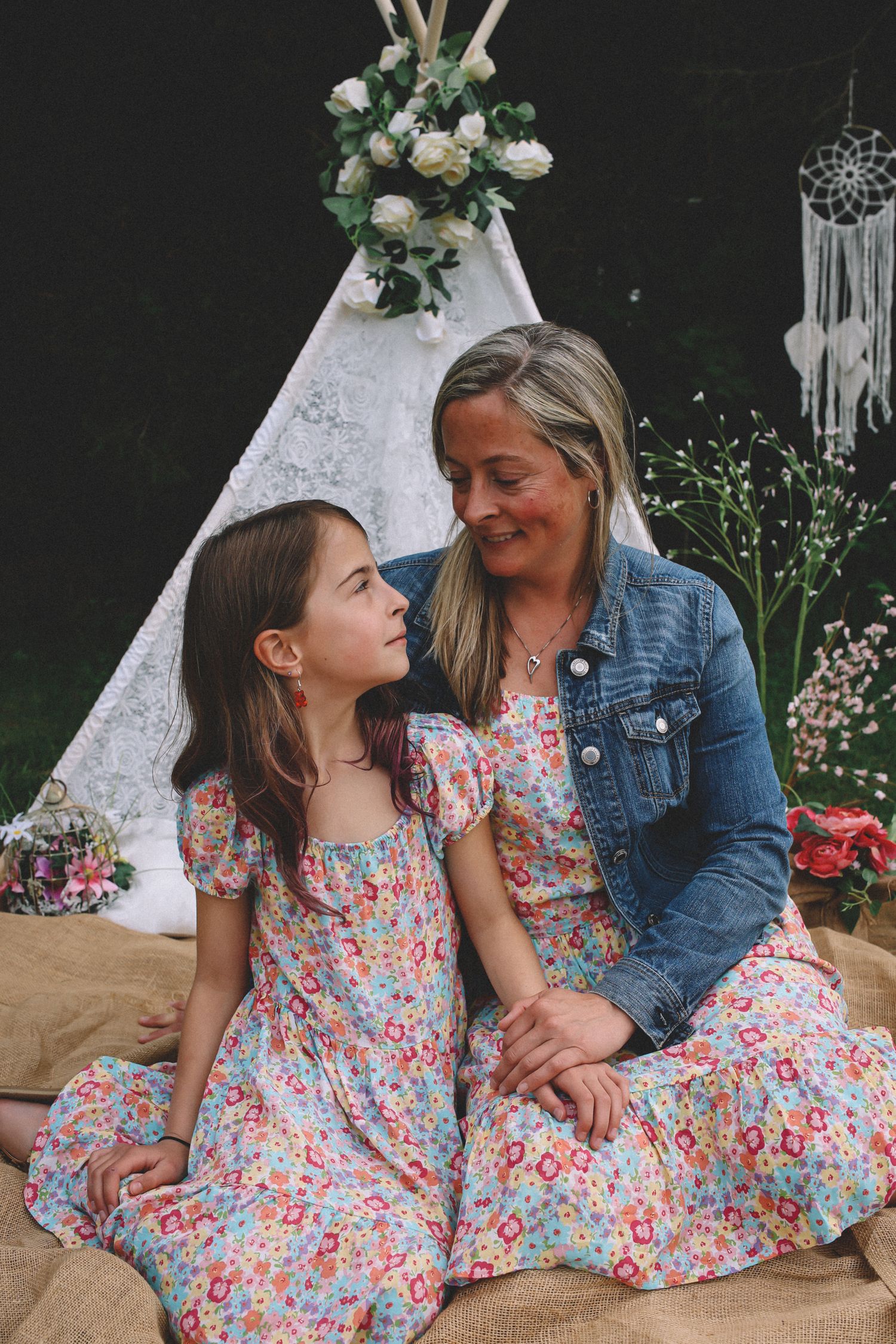 A series of candid moments between two people sitting together in floral and denim outfits against a dark backdrop.