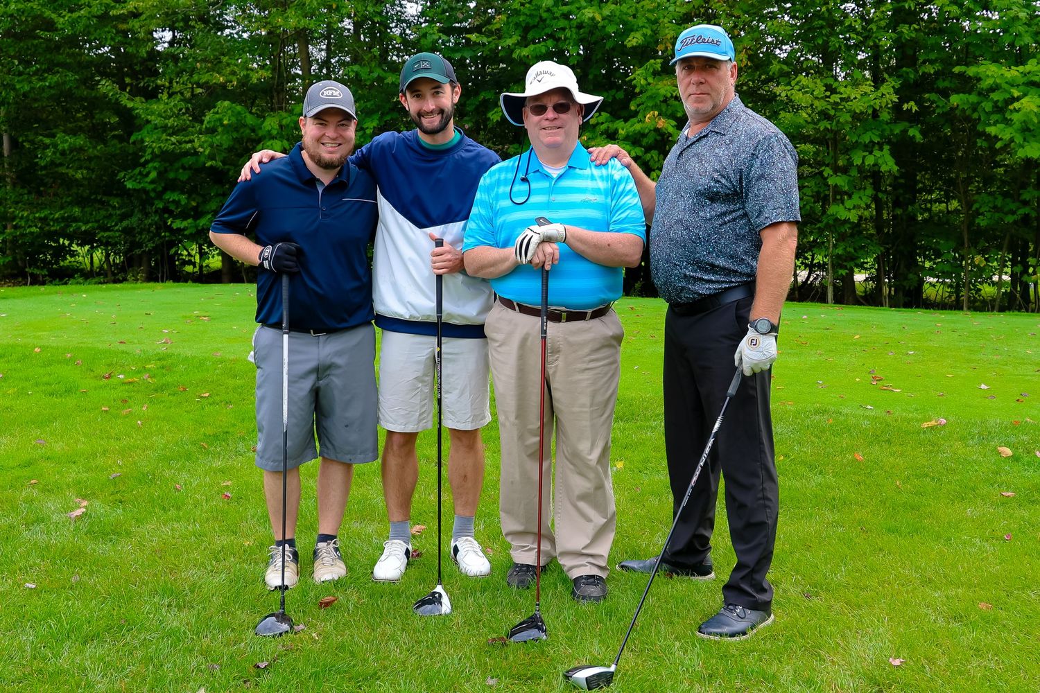 A group of golfers stand together on a lush green course during a golf outing event.