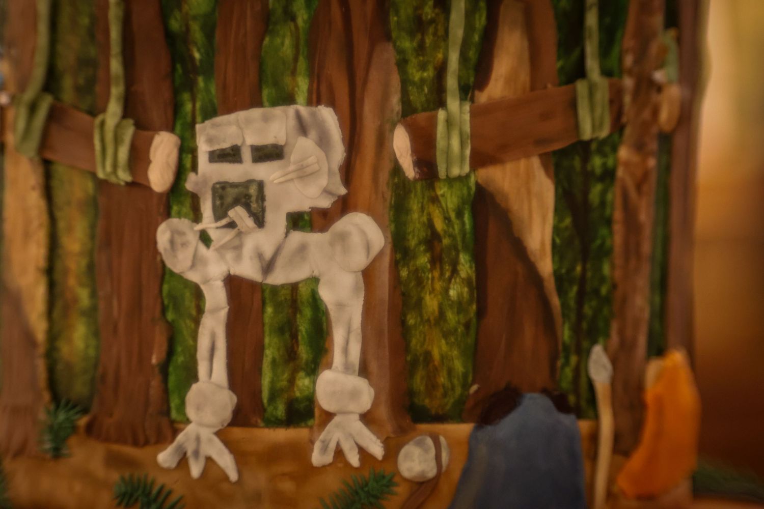 A handmade paper AT-AT walker decoration against a bamboo backdrop in soft focus lighting.