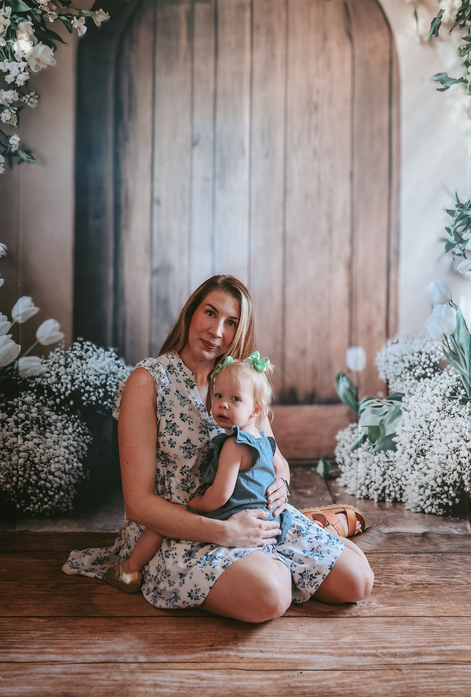 A tender moment captured in a rustic setting with baby's breath flowers decorating the wooden backdrop.