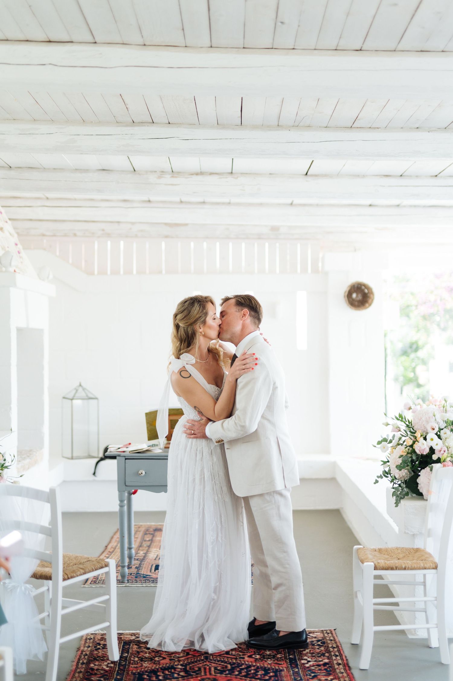 Romantic wedding moments captured on decorative rug in bright white interior.
