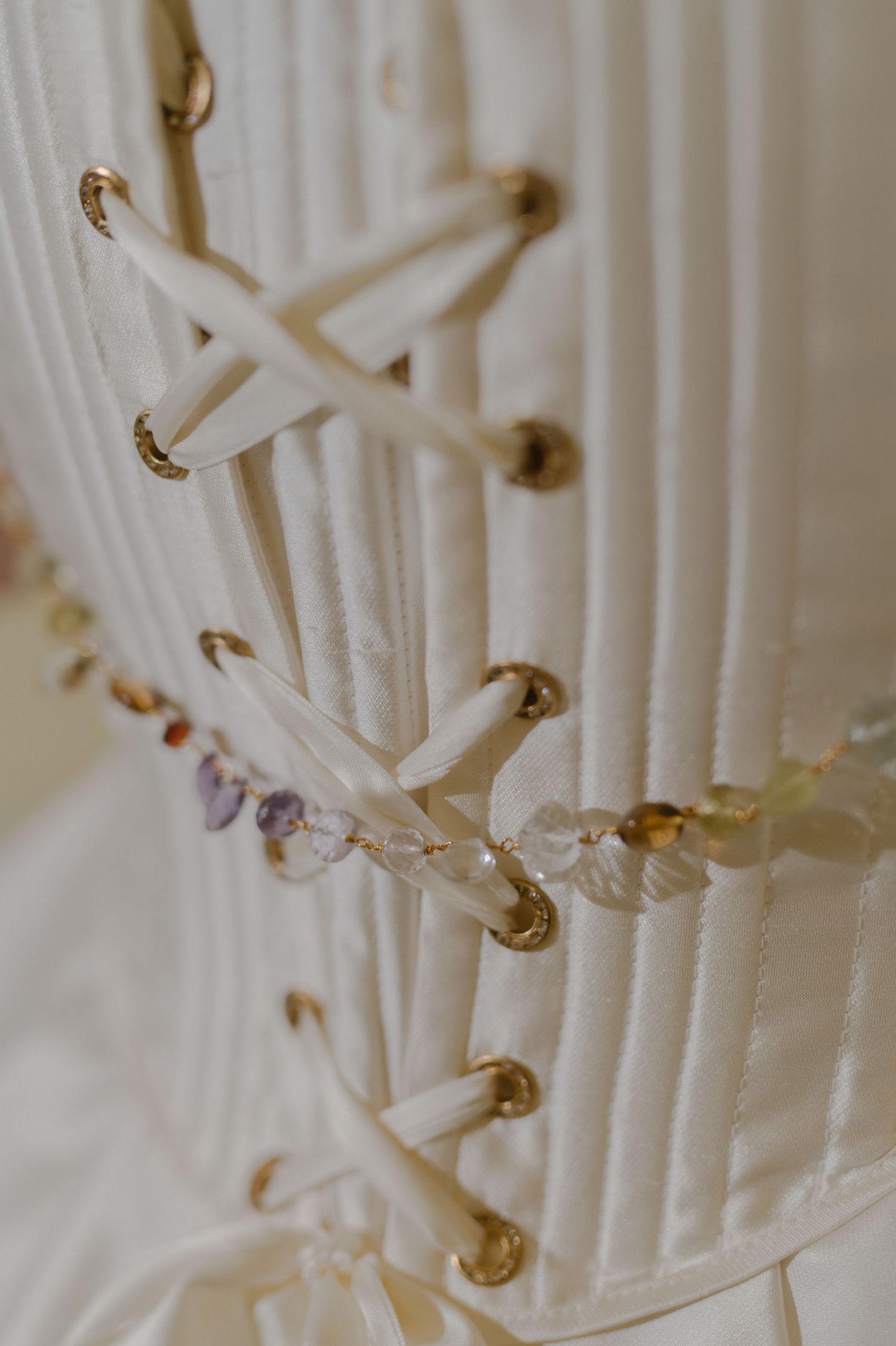 Detailed macro shot of white corset lacing with golden grommets.