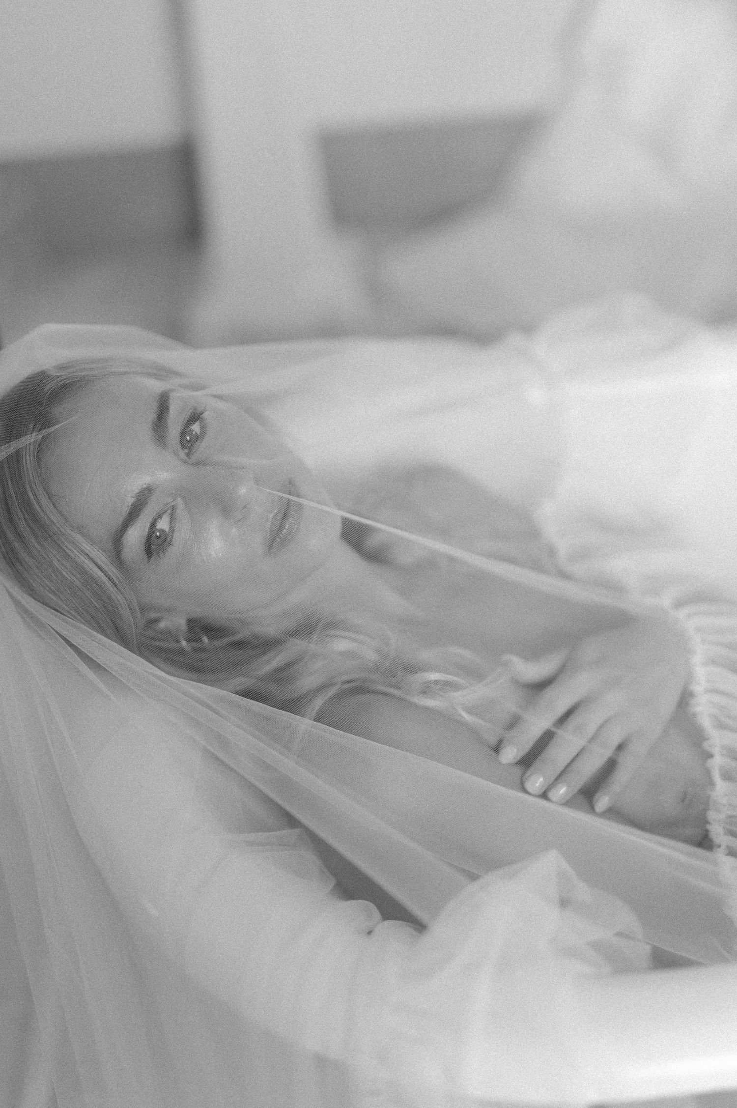 Ethereal bridal portrait through delicate white veil in soft natural light.