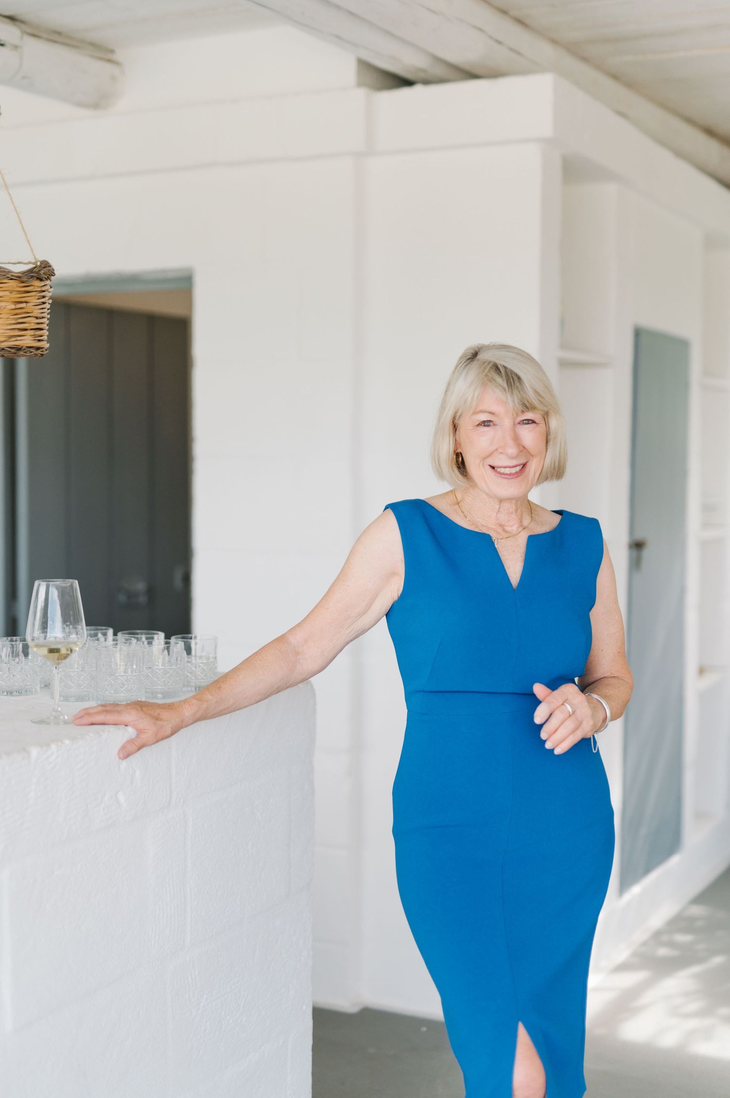 Woman in bright blue dress dancing joyfully in white modern interior space.