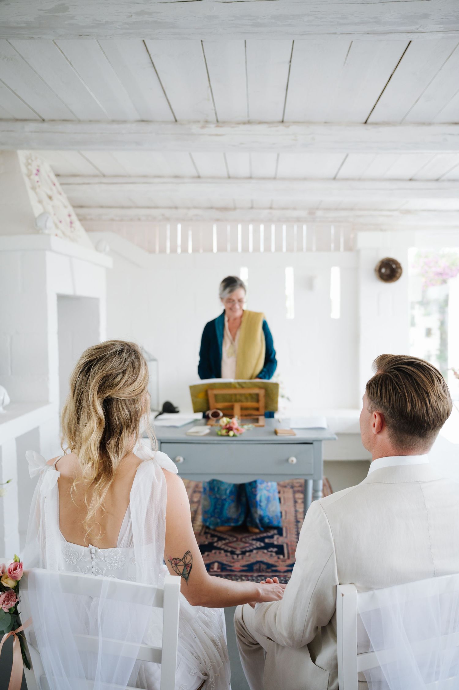 Wedding preparation scene in a bright white room with wooden ceiling.
