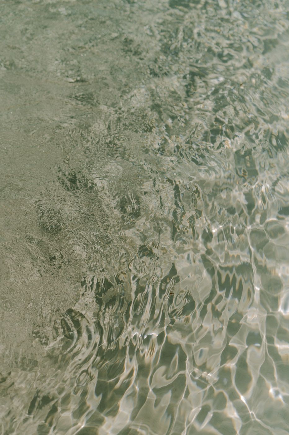 Abstract patterns of sunlight reflecting on rippling water surface.