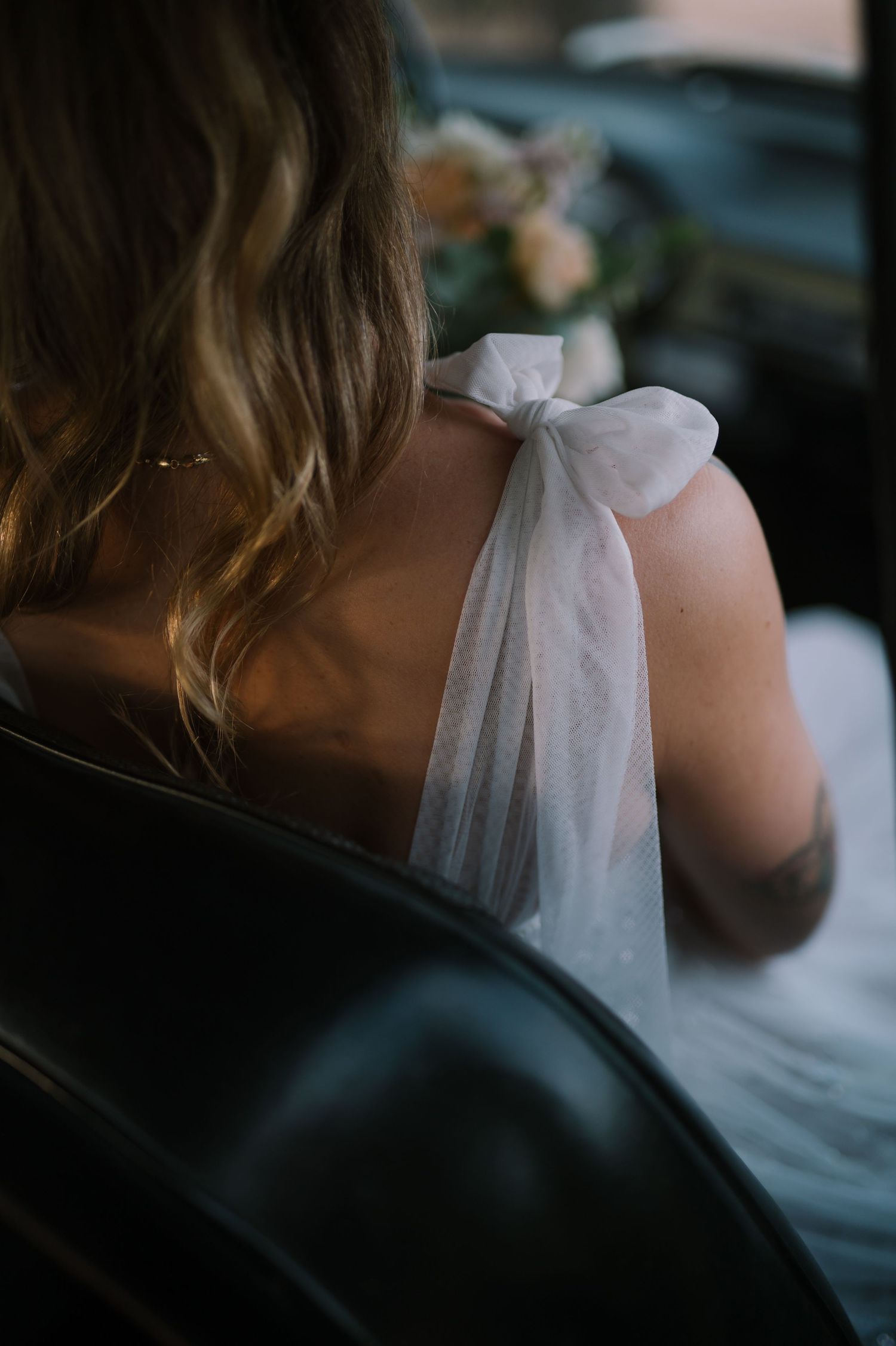 Close-up details of a white wedding dress bow in a car.