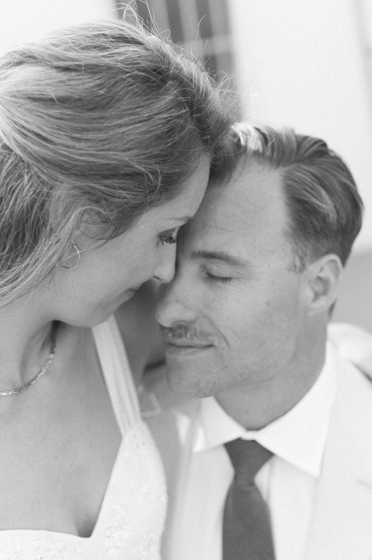 Black and white intimate portrait of newlyweds sharing a tender moment.