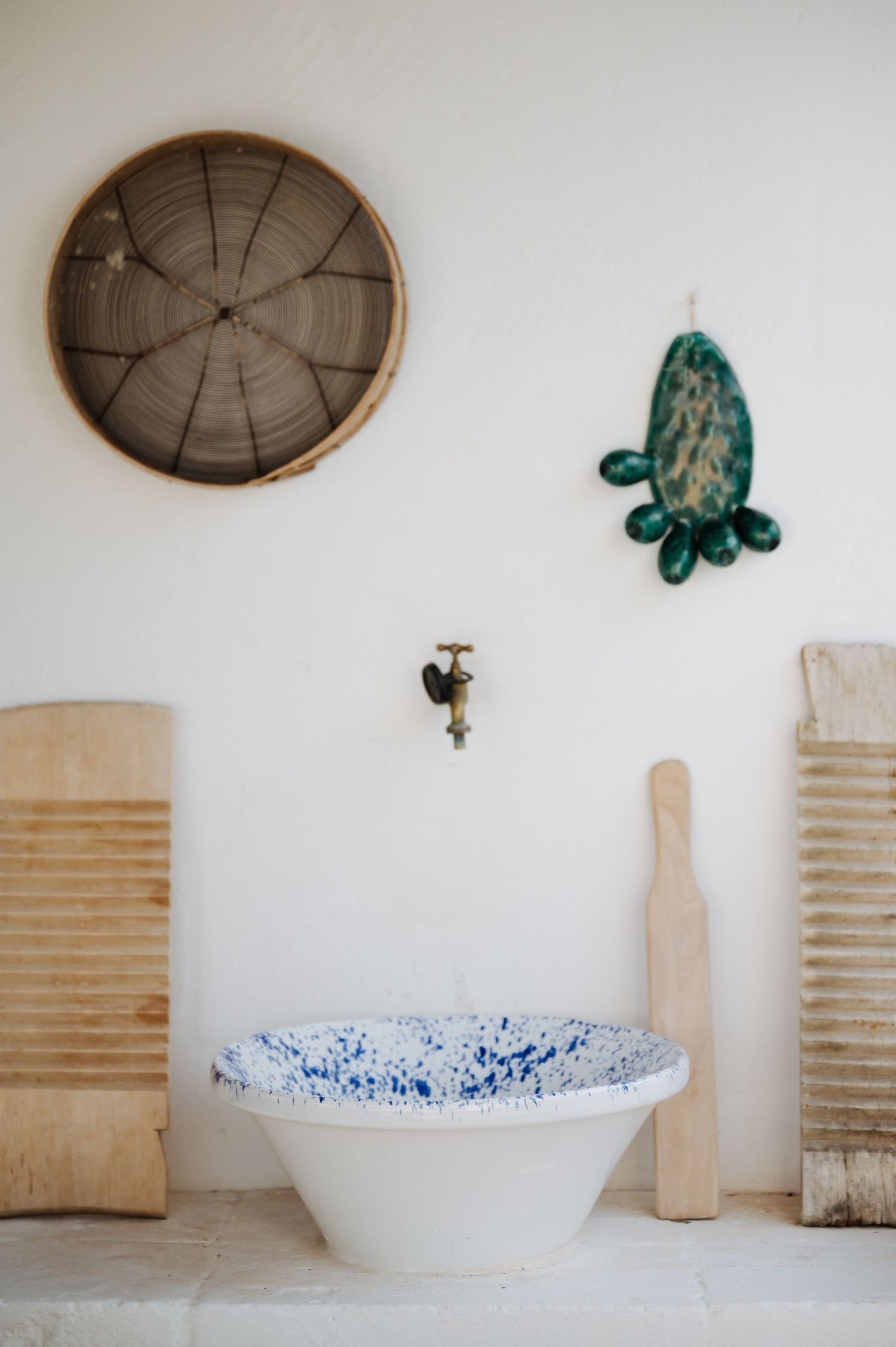 Minimalist white wall decor with wooden accents and blue speckled serving bowl.
