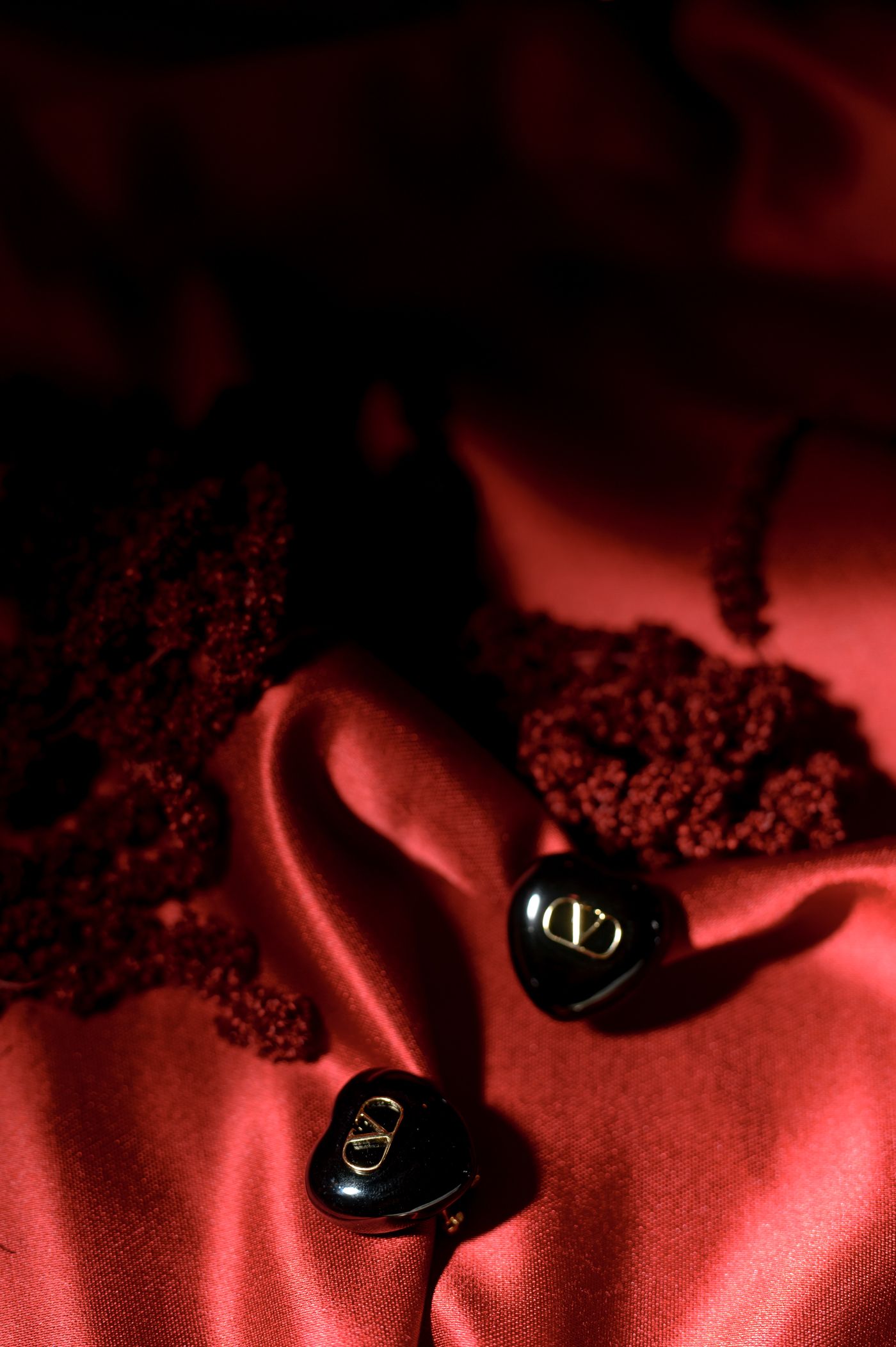 Car keys with keychain resting on red satin fabric in dramatic lighting with shadows.