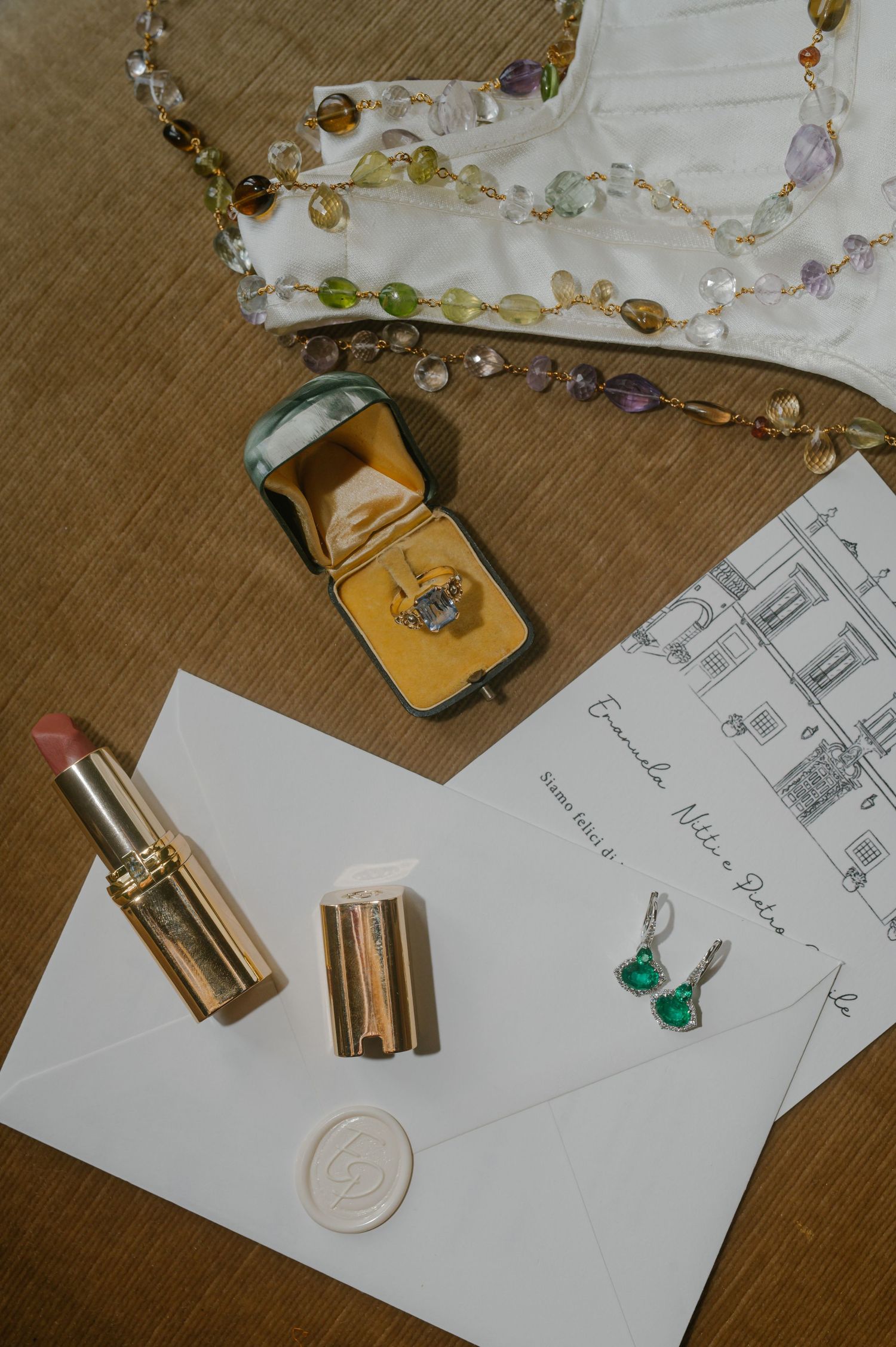 Jewelry making supplies including beads, chains, and sketches laid out on a wooden surface with handwritten notes.