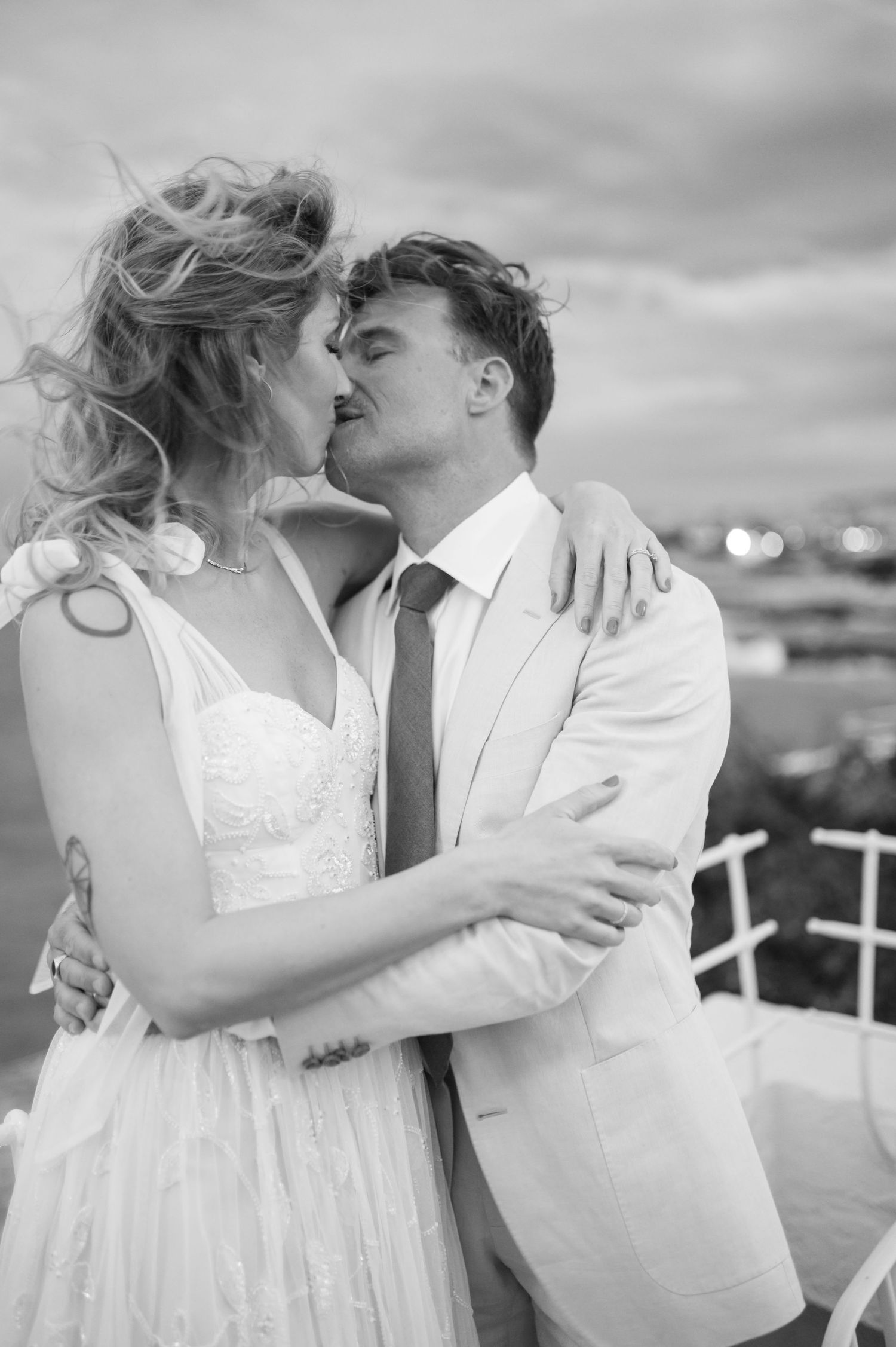 Sequential black and white images capturing tender moments between newlyweds on a seaside terrace.