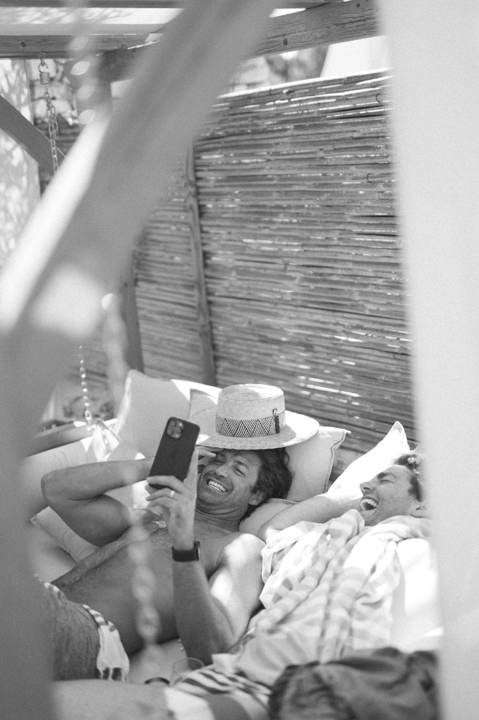 People relaxing on lounge chairs in a shaded outdoor area.