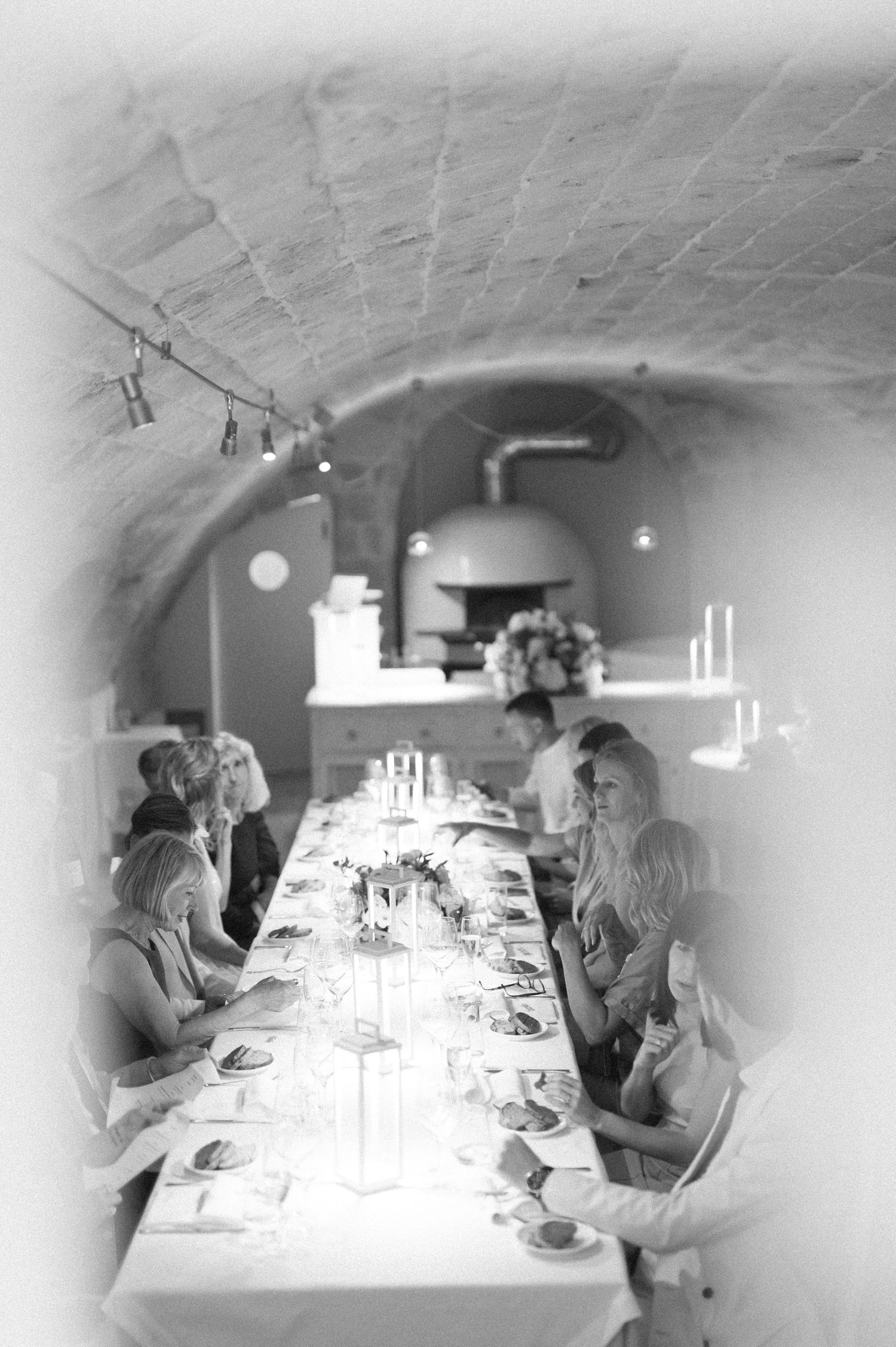 Wedding reception dinner in a rustic vaulted cellar with elegant table settings.