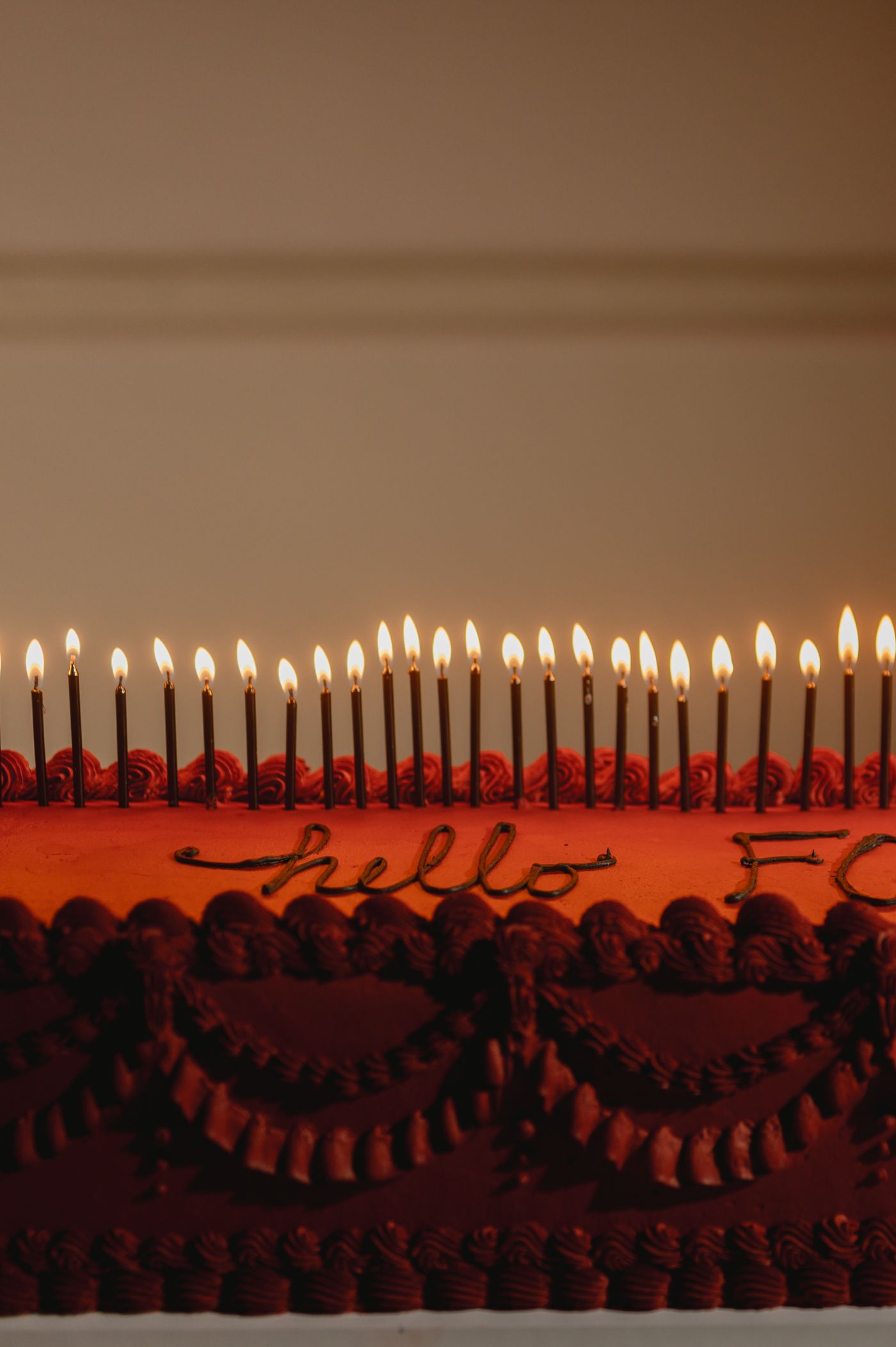 A sequence of lit candles arranged in a row create a warm glowing reflection against a dark background.