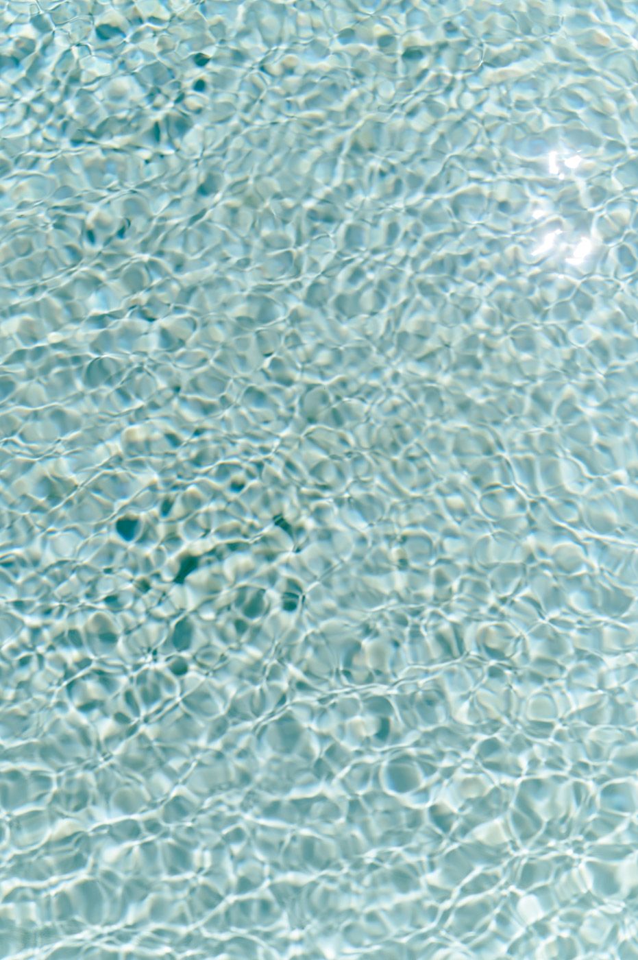 Rippling turquoise water surface with sunlight creating mesmerizing patterns.
