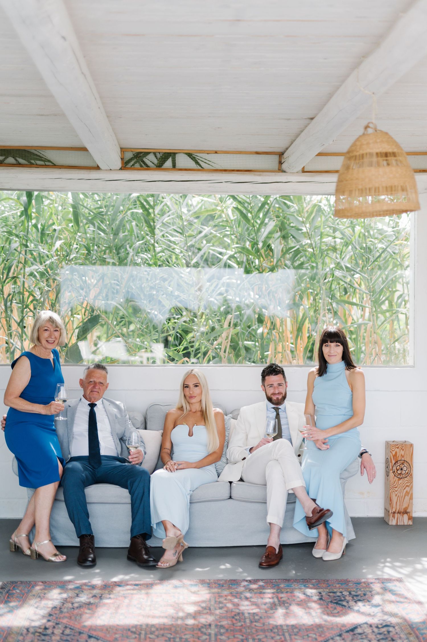 Wedding party lounging on white outdoor sofa in casual poses.
