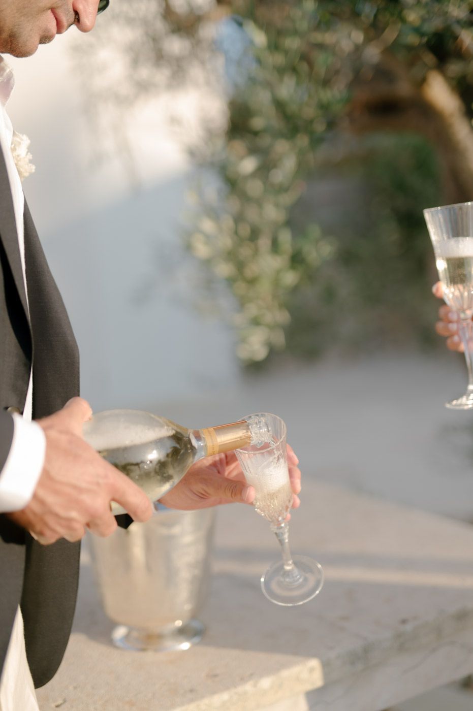 Hands holding champagne glasses during an outdoor celebration.