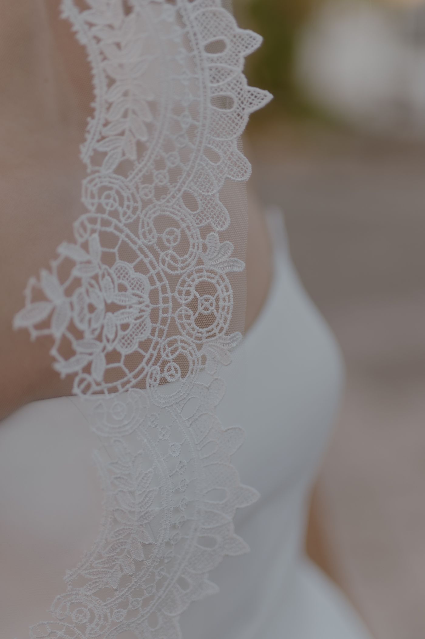 Close-up view of delicate white lace trim detail against a soft blurred background.
