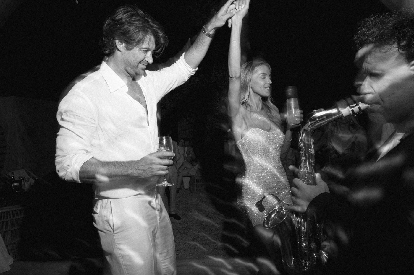 Wedding guests dancing and celebrating at an evening reception.