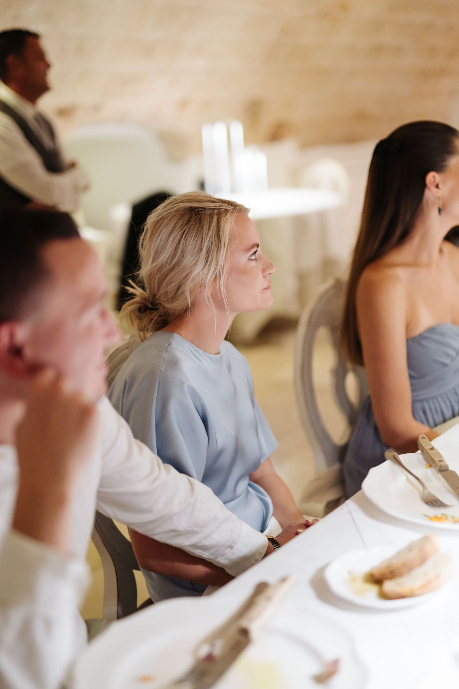 Wedding guests seated at elegant white-clothed tables during reception dinner.