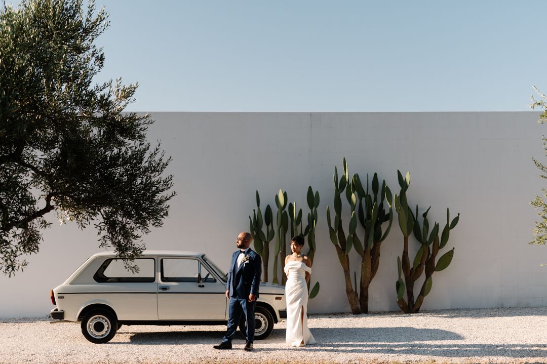Vintage van parked against white wall with desert cacti creating modern wedding scene.