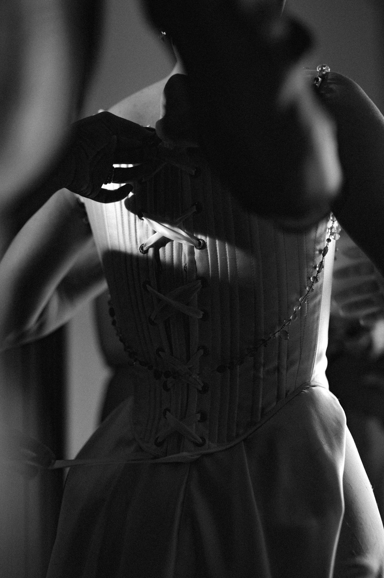 Black and white detail of a corset or dress bodice with intricate stitching.