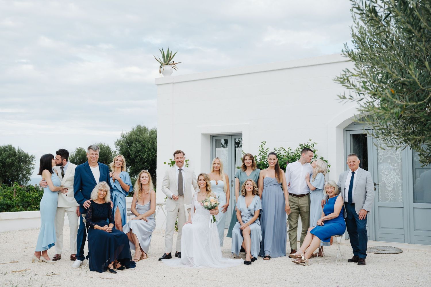 Wedding celebration group gathered outside white Mediterranean style architecture.