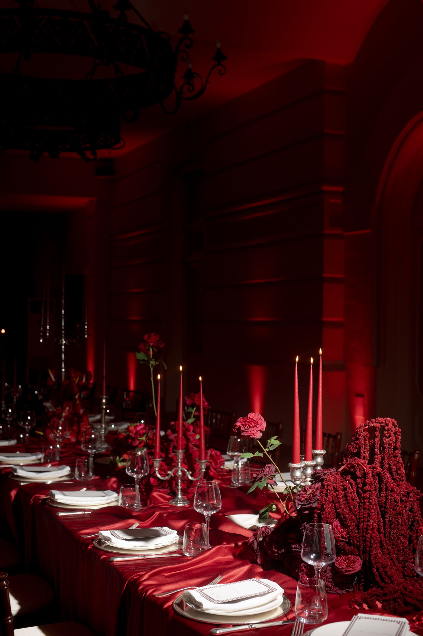 Elegant table settings in dark room with dramatic red lighting and white place settings create a luxurious dining atmosphere. red trend