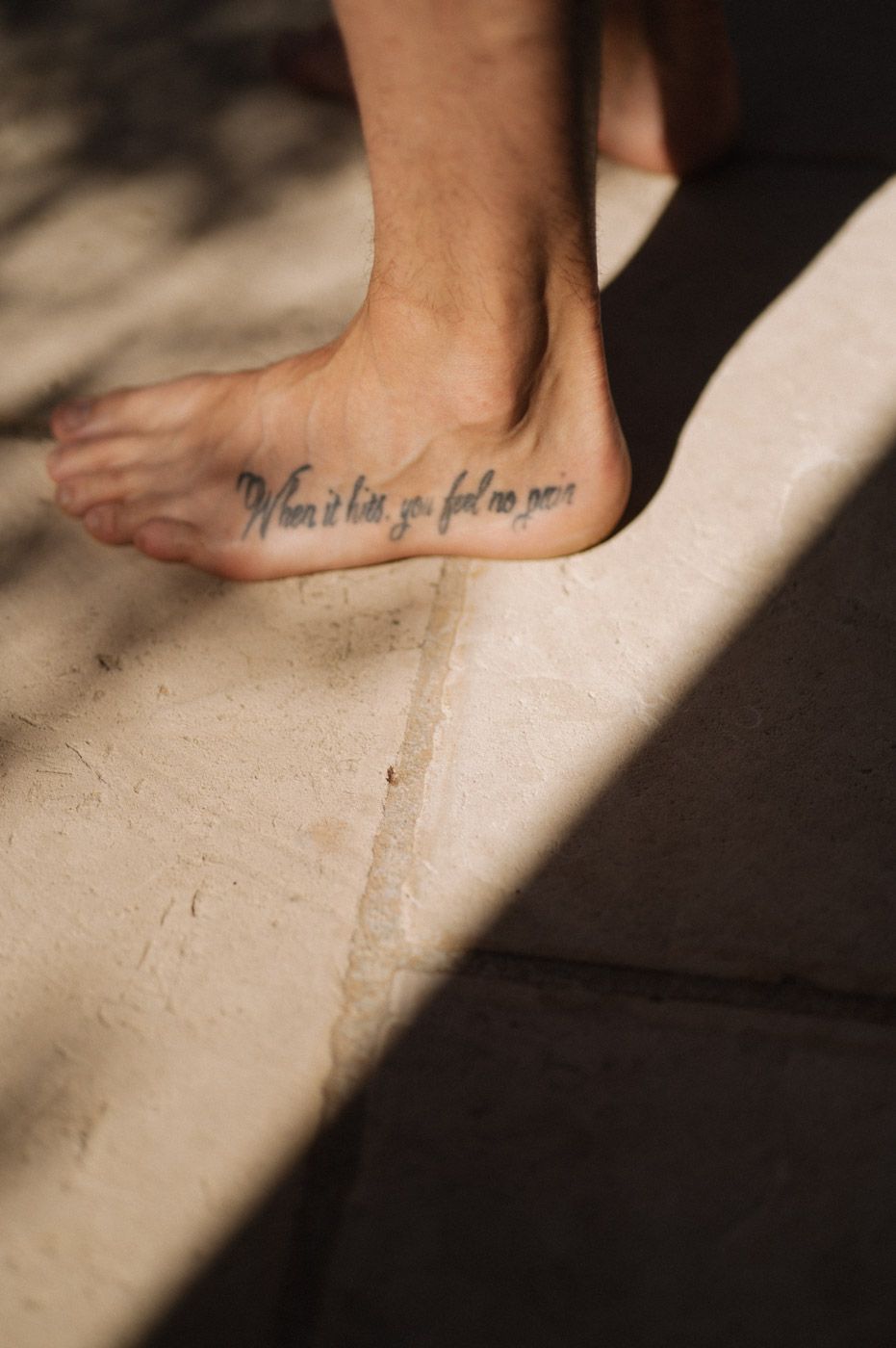 Close-up of a tattoo on someone's foot in dramatic lighting.