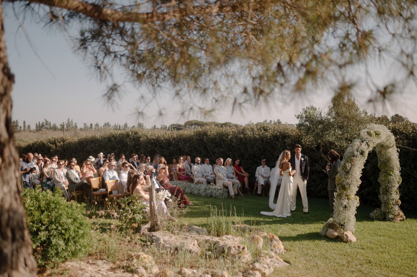 Panoramic view of wedding guests gathered in an outdoor garden setting.