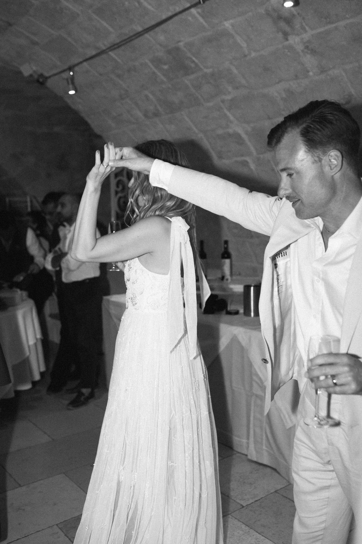 Wedding party dancing and celebrating in a stone-walled reception venue.
