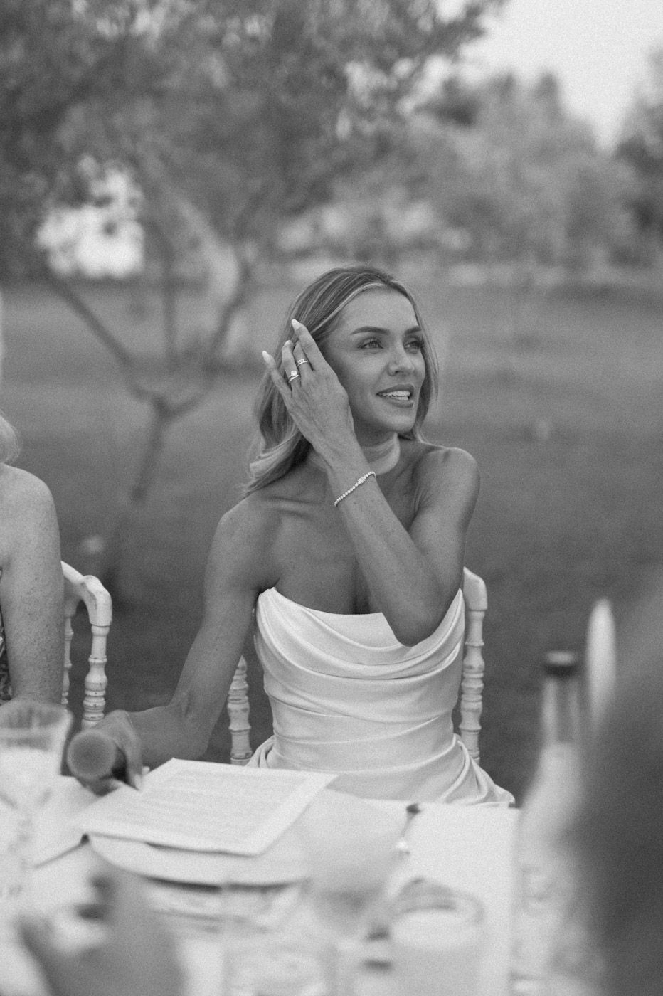 Black and white candid photos of wedding guests enjoying dinner conversation at an outdoor reception.