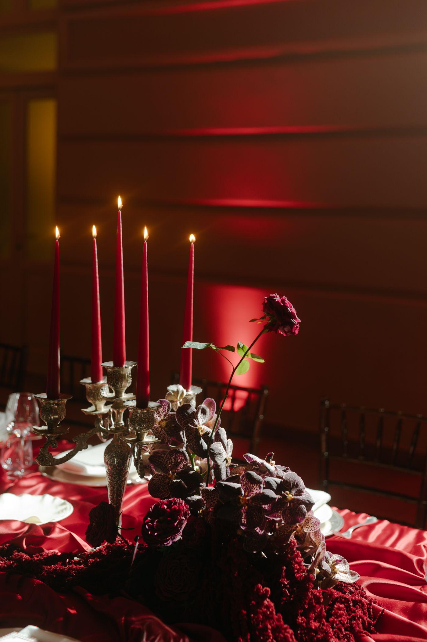 A sequence of moody photos showing lit candles and dark red roses on a reflective surface in dramatic lighting.