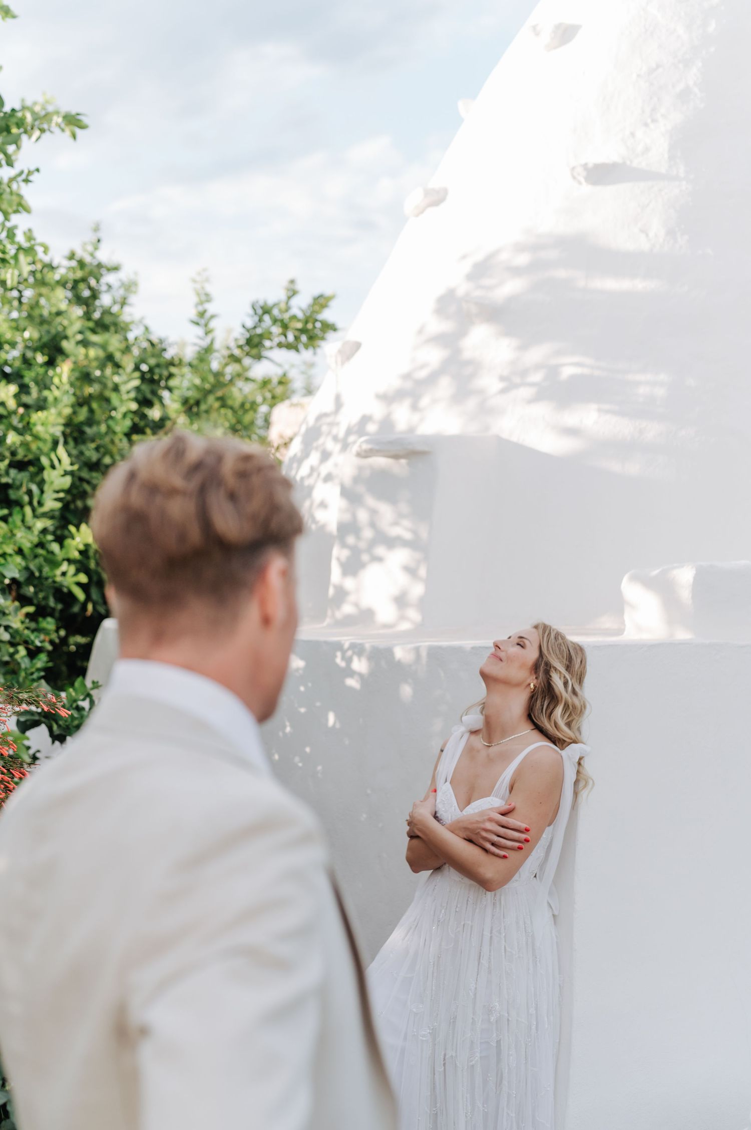 Candid wedding moment captured outside a white Mediterranean-style building.