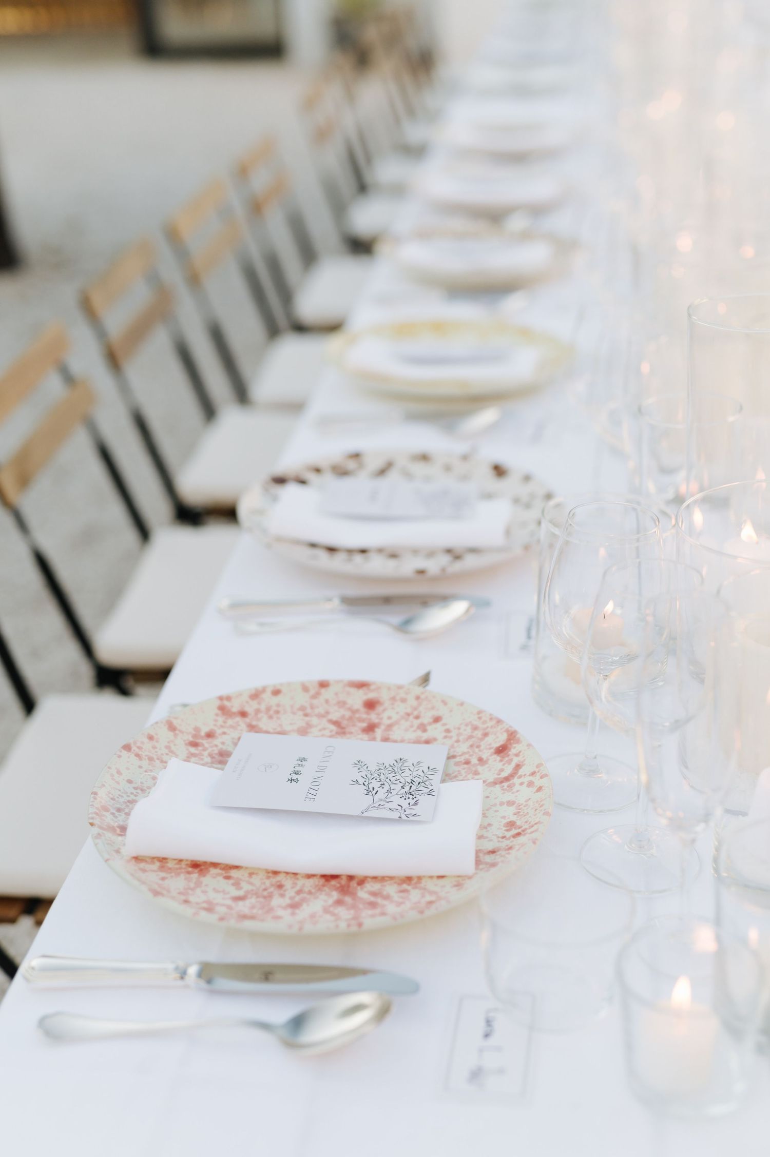 Elegant table settings with white plates and pink floral accents at a formal dining event.