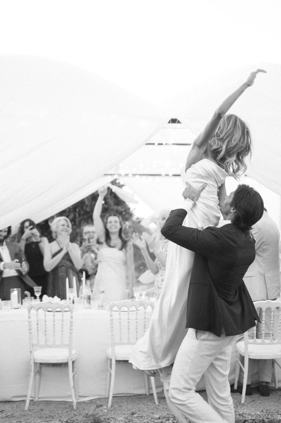 Dancing silhouettes celebrate at an outdoor wedding reception with white decor.