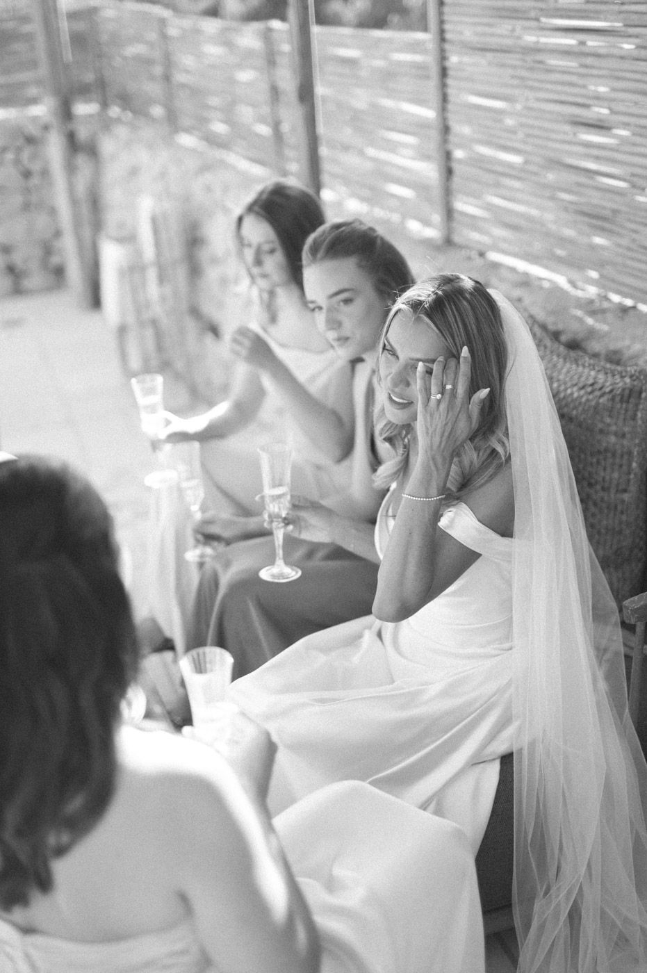 Wedding party toasting with champagne glasses under covered patio.