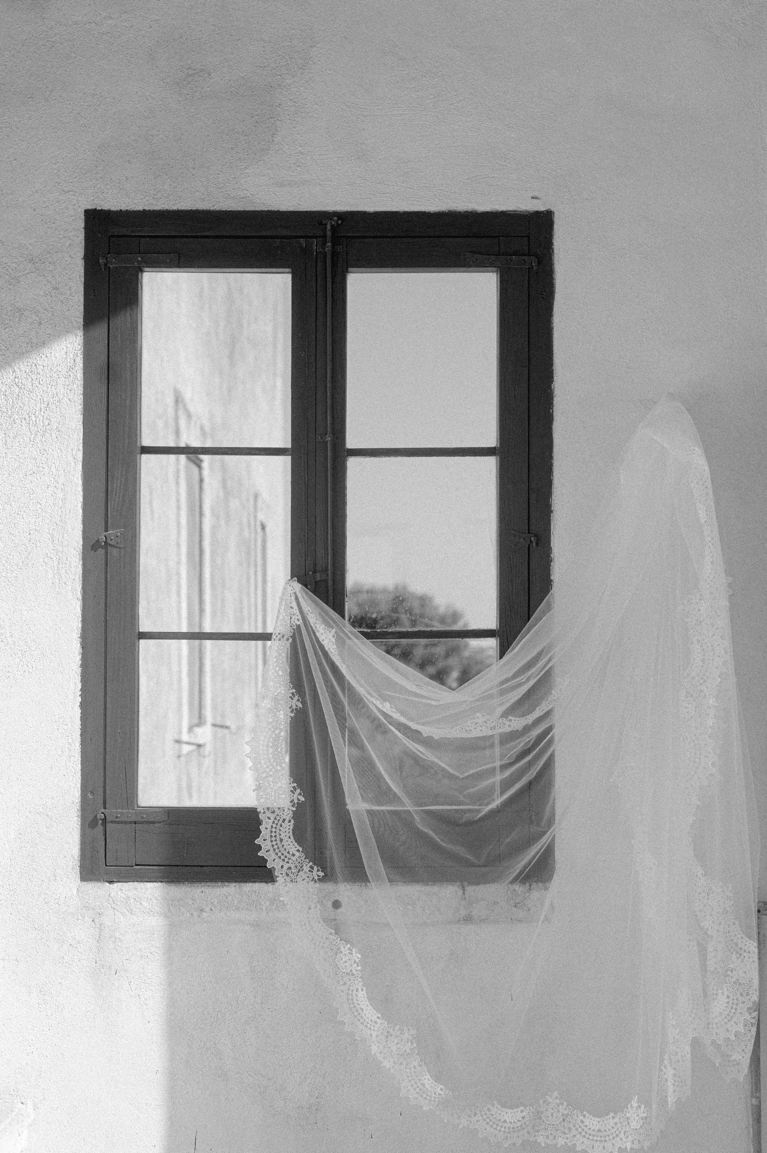 A series of black and white photographs showing white curtains billowing through dark windows in a minimalist setting.