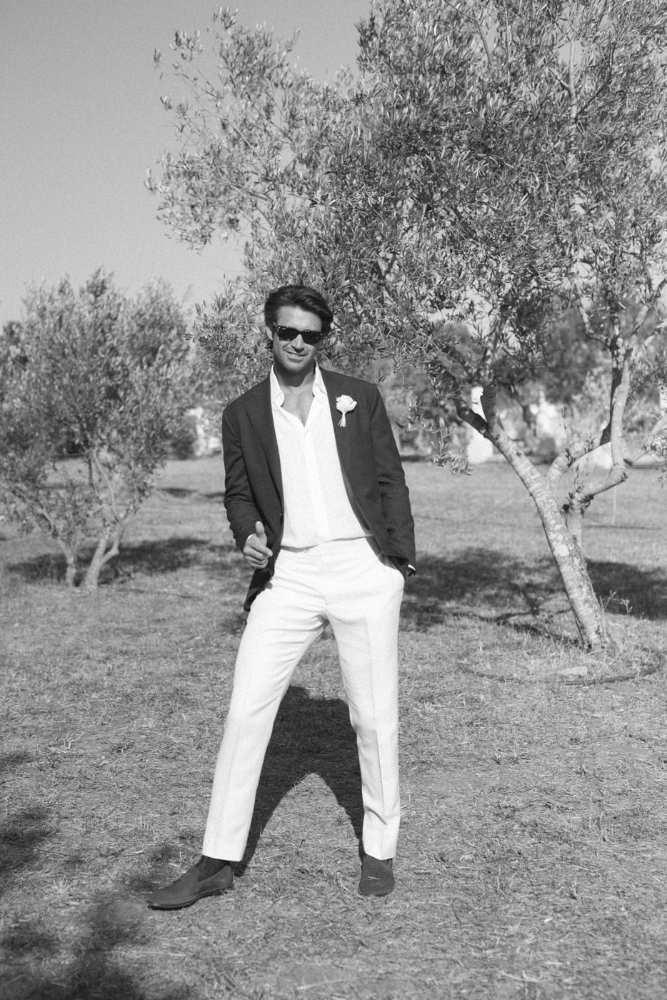 Stylish groomsmen posing in black and white among olive trees.