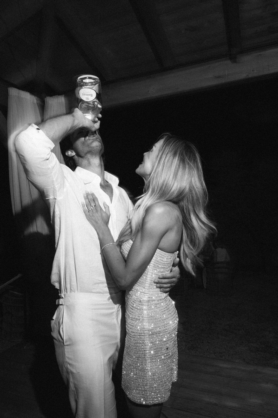 A couple dancing together at an event, with one person in white and the other in a sparkly dress.
