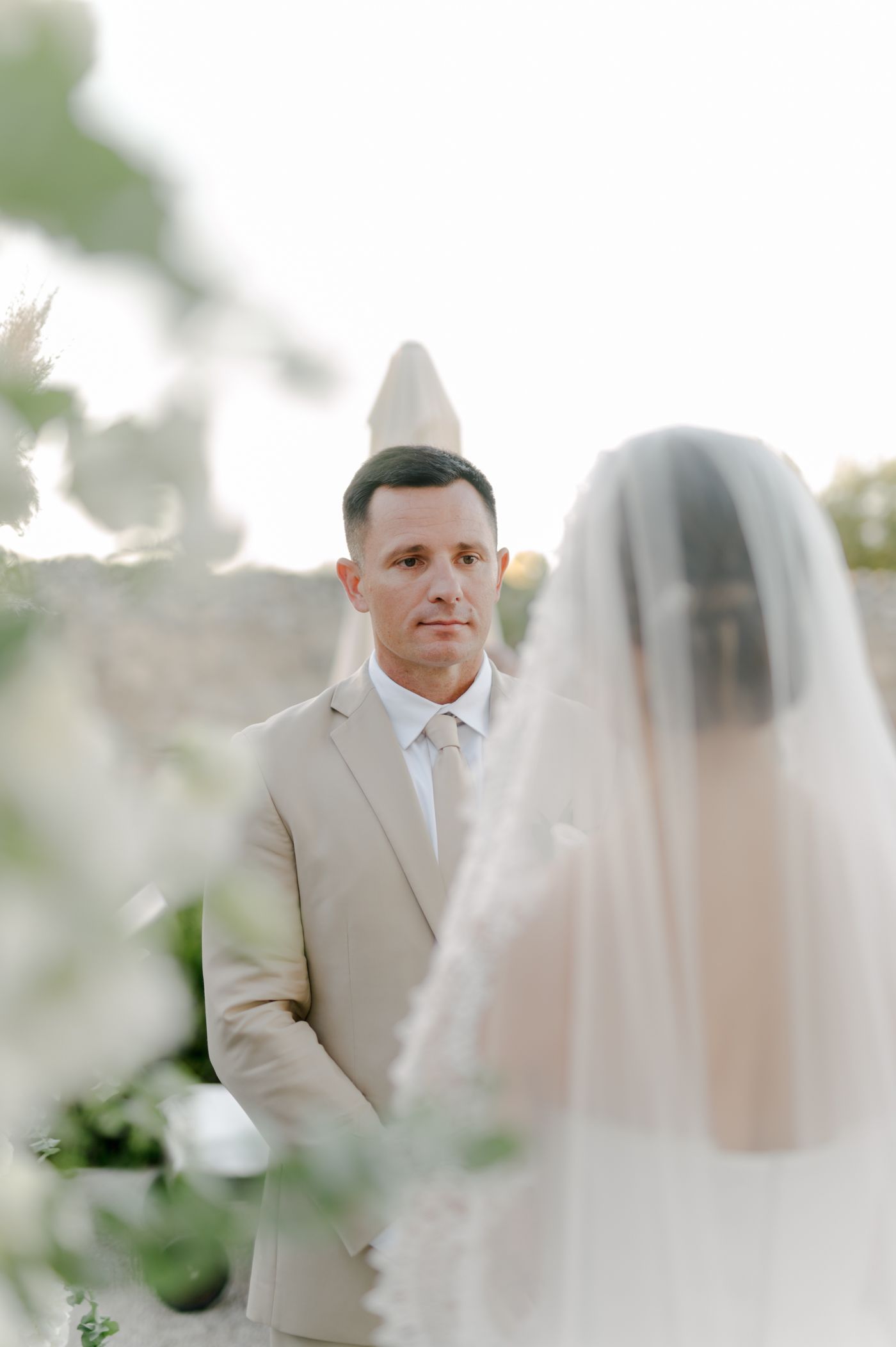 A romantic wedding moment captured as a couple shares intimate glances through a delicate white veil.