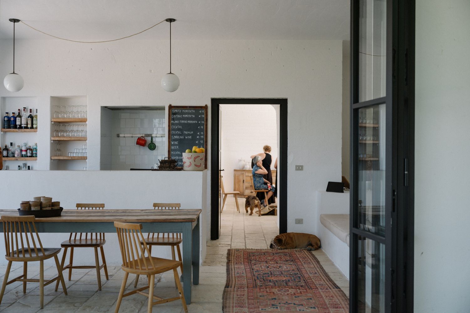Modern minimalist interior with white walls, wooden furniture, and vintage rugs creating a warm contemporary living space.