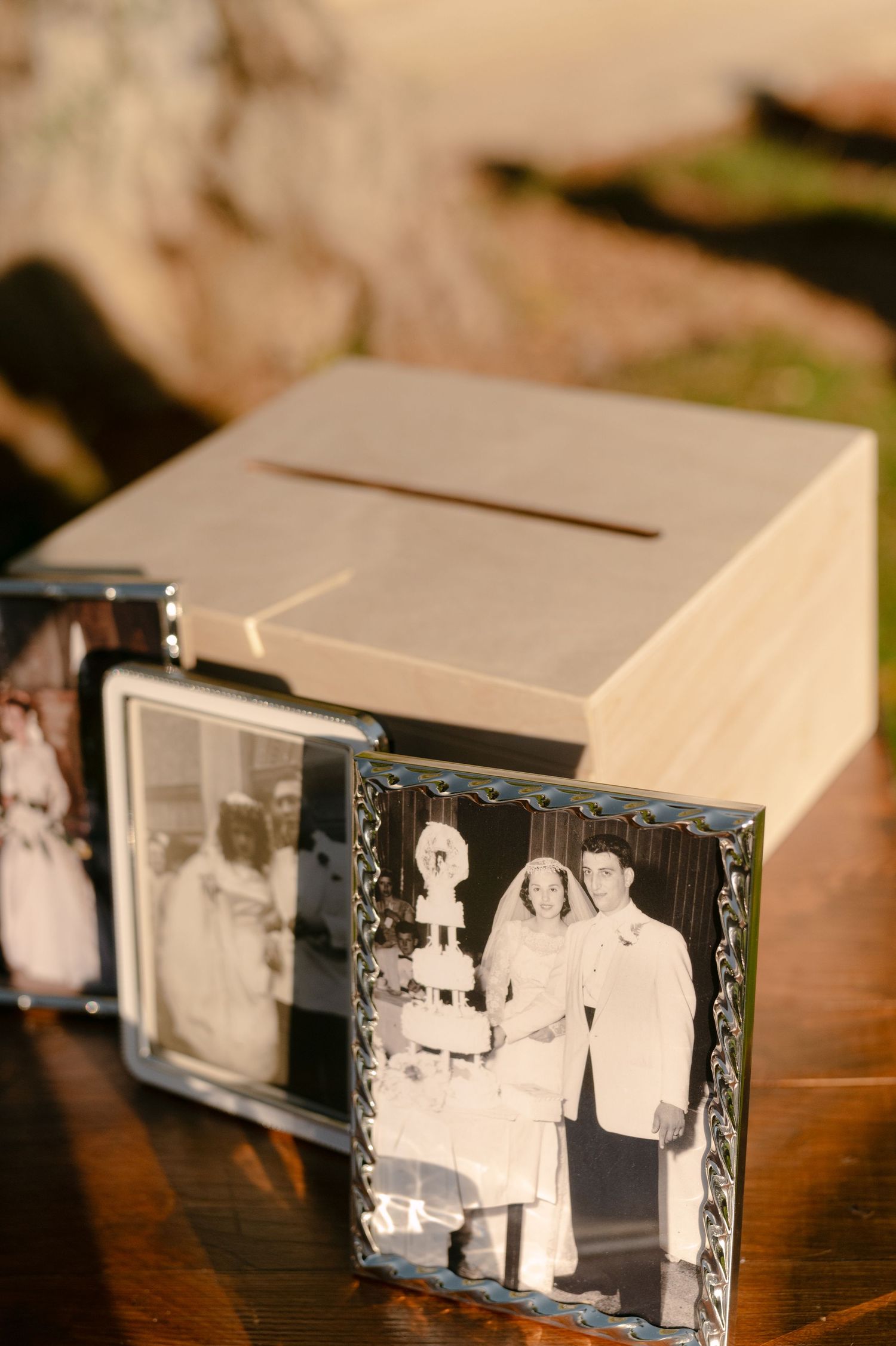 Vintage black and white wedding photo in silver frame displayed beside a wooden card box on a table.