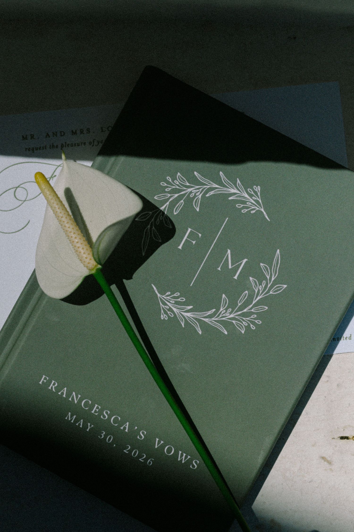 Green wedding vow book with floral monogram F|M, Francesca's Vows May 30 2026, with white calla lily.