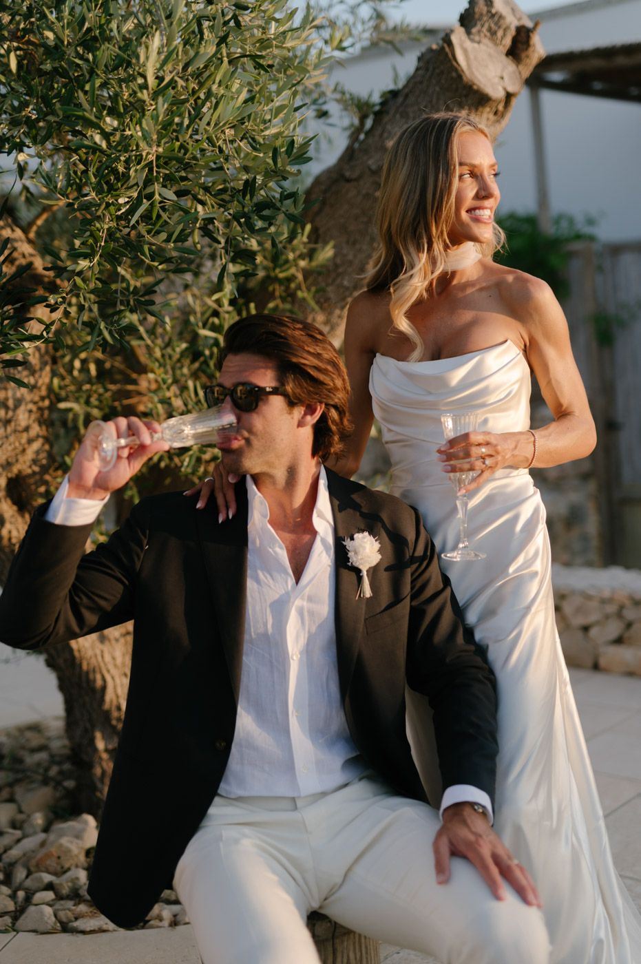 A couple shares a playful moment together against an olive tree backdrop at sunset.