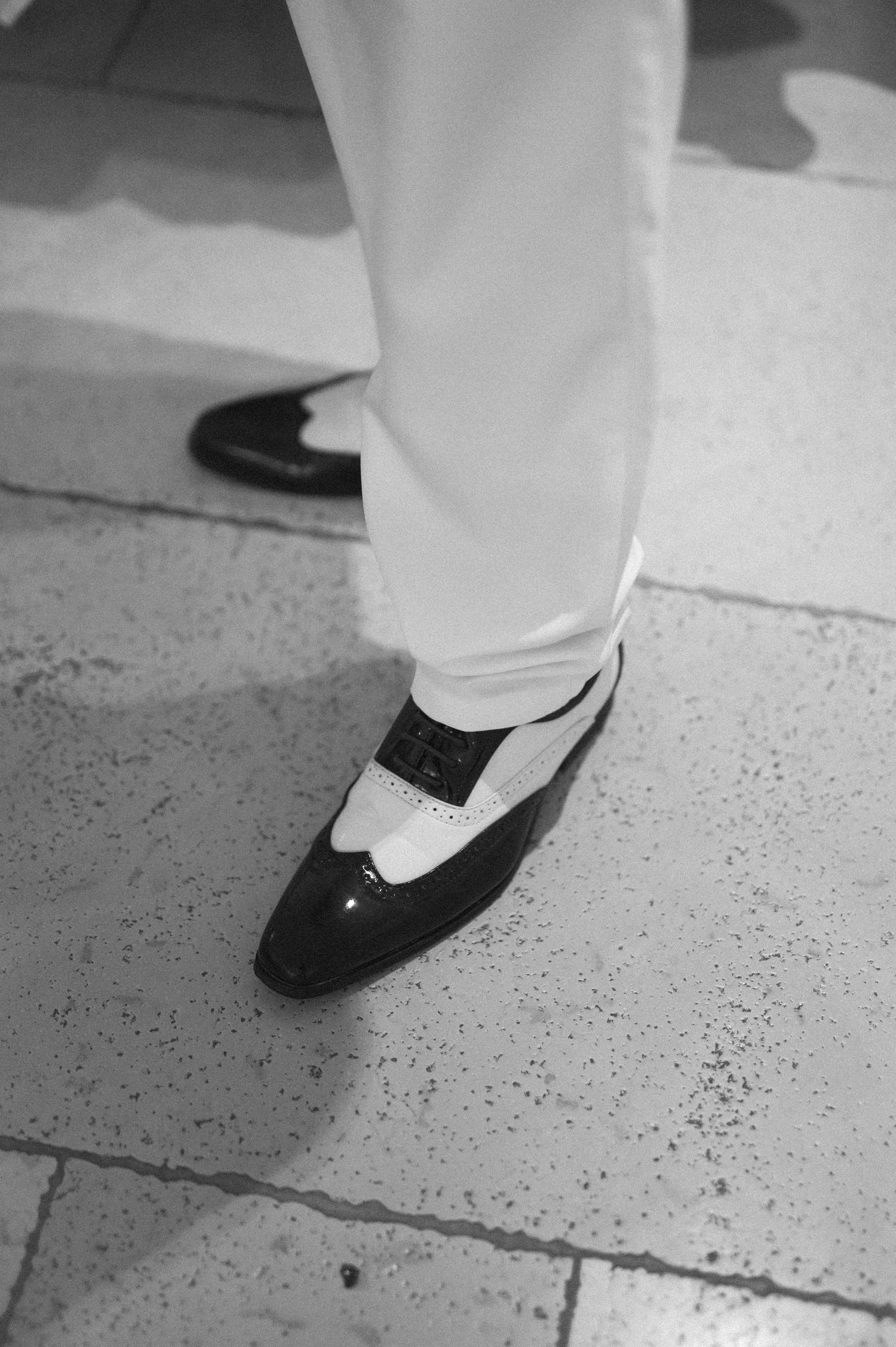 Black and white detail shot of formal shoes on stone flooring.