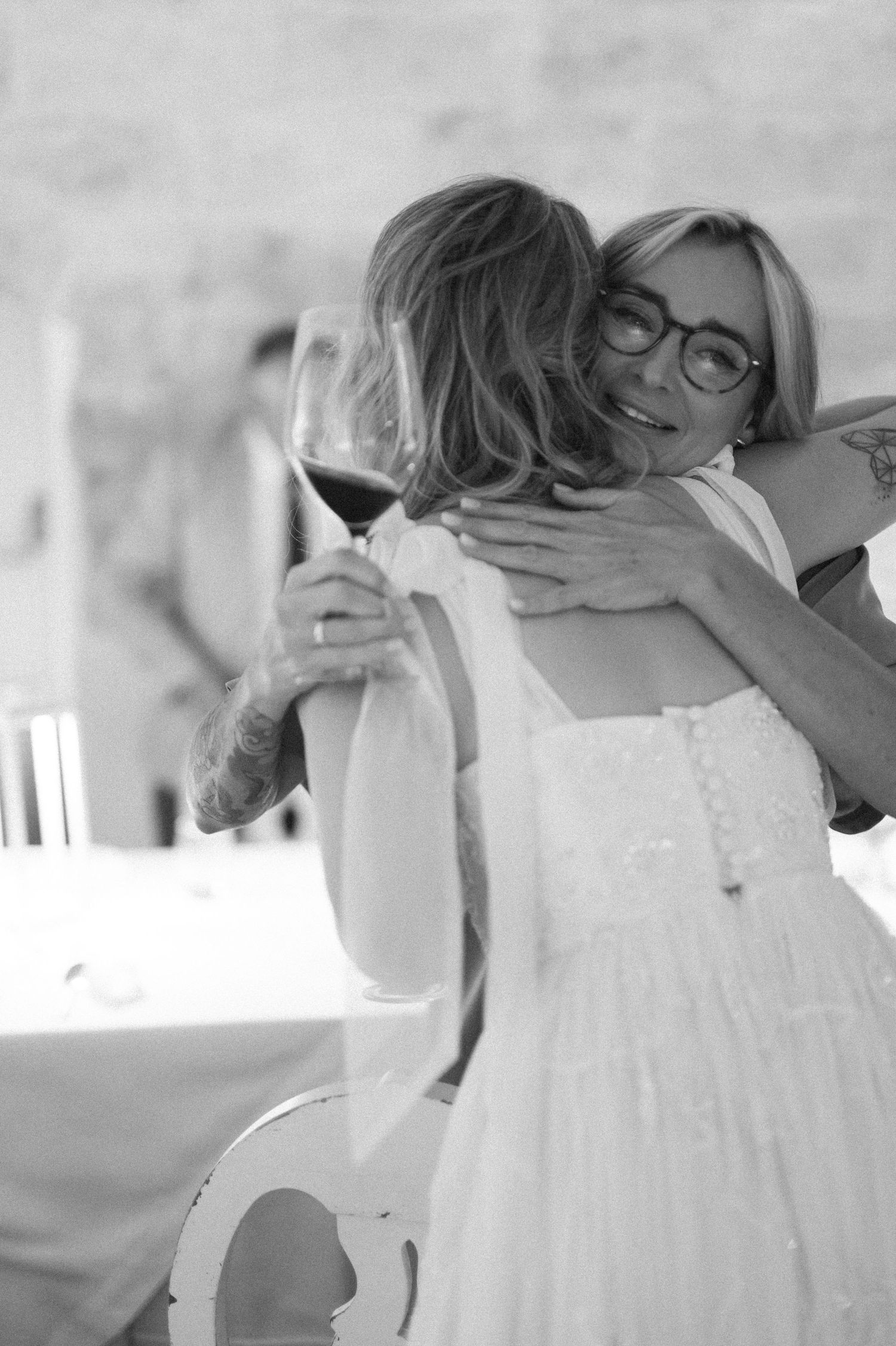 Women in white dresses embracing during an emotional wedding moment.