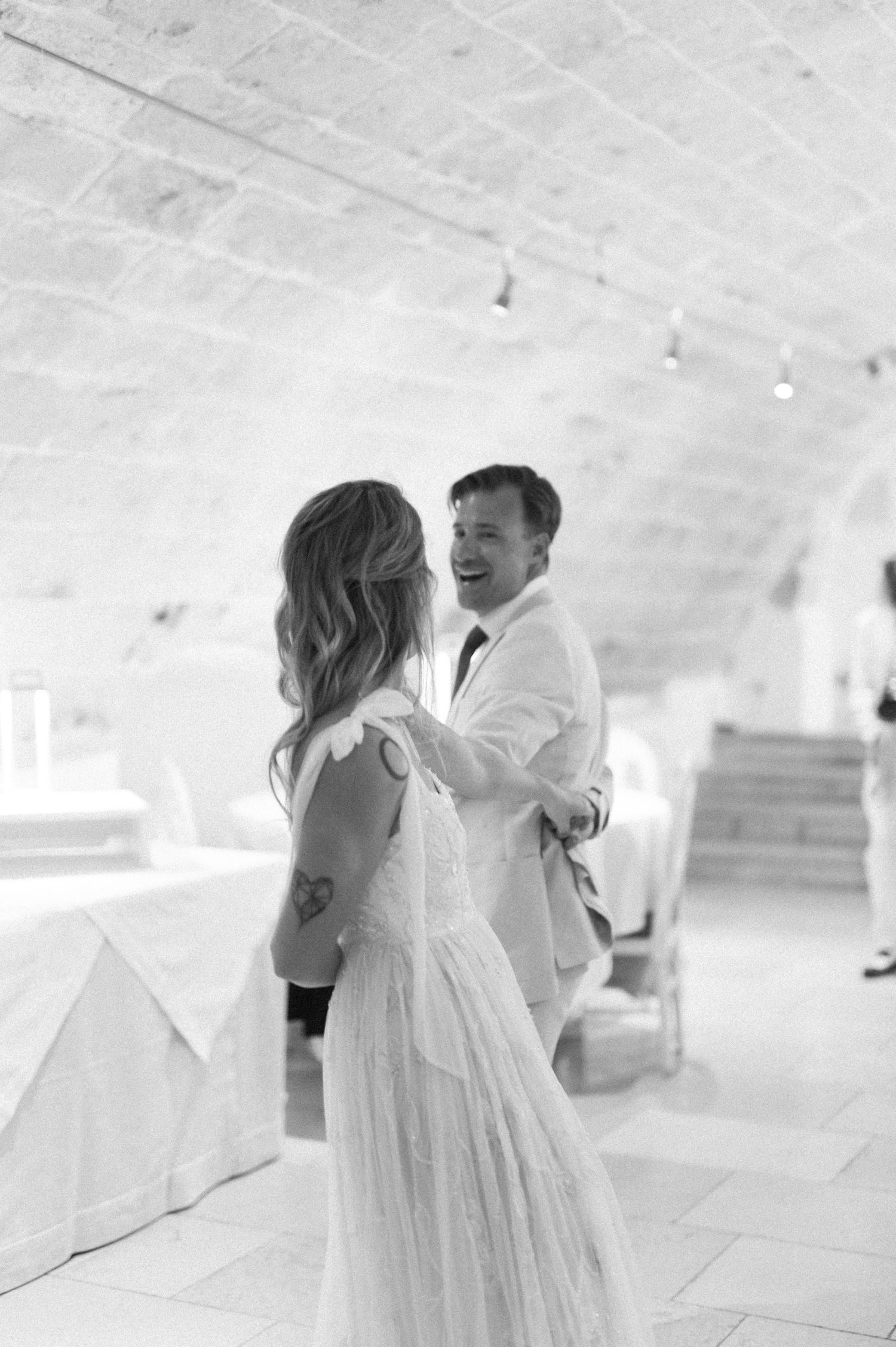 Couple dancing together in an elegant white vaulted reception space.